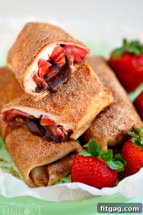 Crispy Chocolate Strawberry Cheesecake Chimis 6 A plate of two Chocolate Strawberry Cheesecake Chimichangas, garnished with fresh strawberries and a light dusting of powdered sugar.