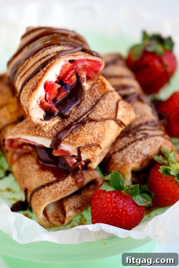 Crispy Chocolate Strawberry Cheesecake Chimis 7 Close-up of a cut Chocolate Strawberry Cheesecake Chimichanga, showing the layers of strawberry cream cheese, fresh strawberries, and chocolate filling.
