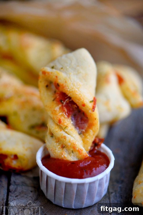Savory Pepperoni Pizza Spirals 4 A hand dipping a crispy Pepperoni Pizza Twist into a small bowl of marinara sauce