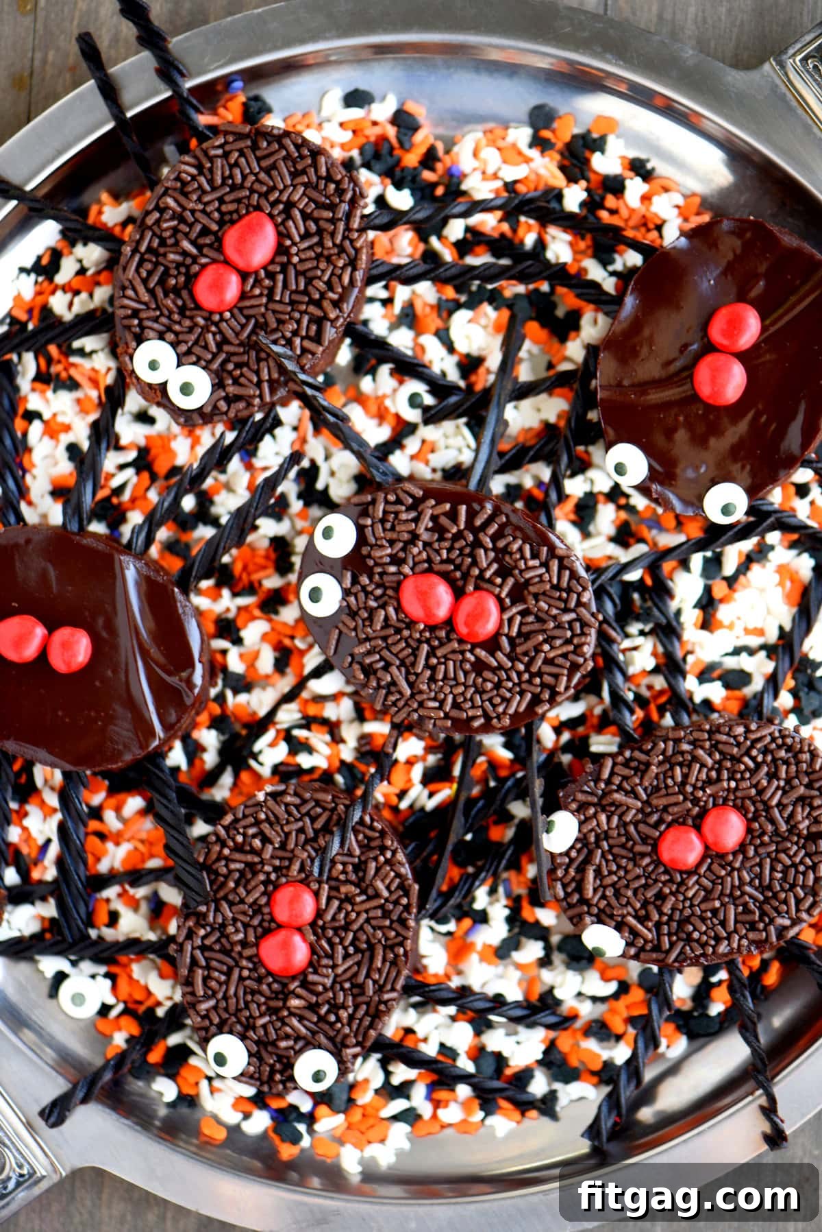 Black Widow's Midnight Fudge Bites 5 Top-down view of a tray filled with brownies cut into spider shapes, artfully placed on colorful Halloween sprinkles.