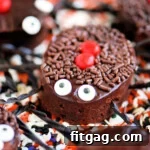 black widow brownie topped with chocolate ganache, candy eyes and licorice legs sitting on a bed of halloween sprinkles.
