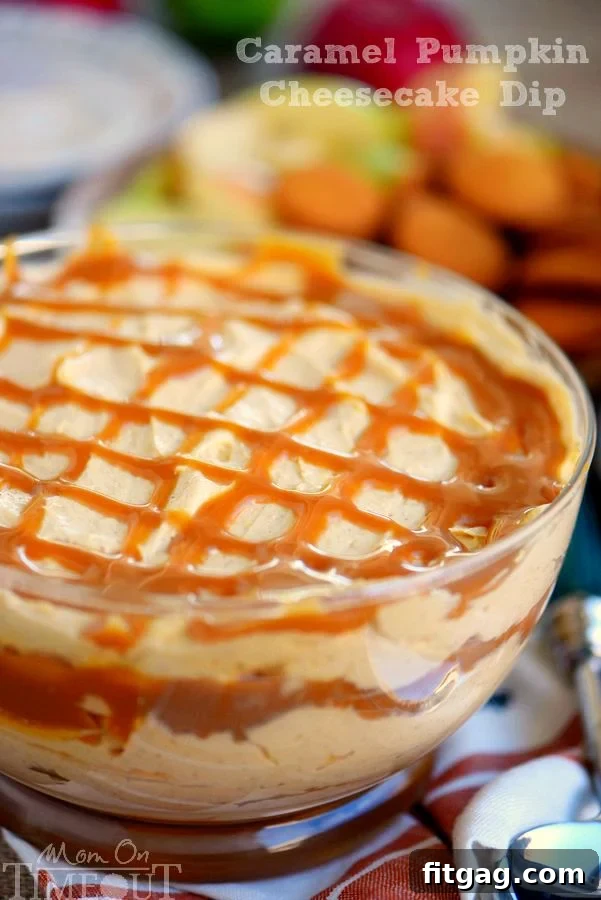 A creamy Caramel Pumpkin Cheesecake Dip in a clear serving bowl, elegantly drizzled with a rich caramel sauce on top. Perfect for fall entertaining.