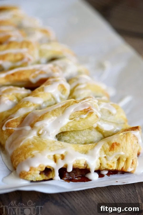 Close-up of golden puff pastry with apple and walnut filling peeking through the woven top, ready for baking.