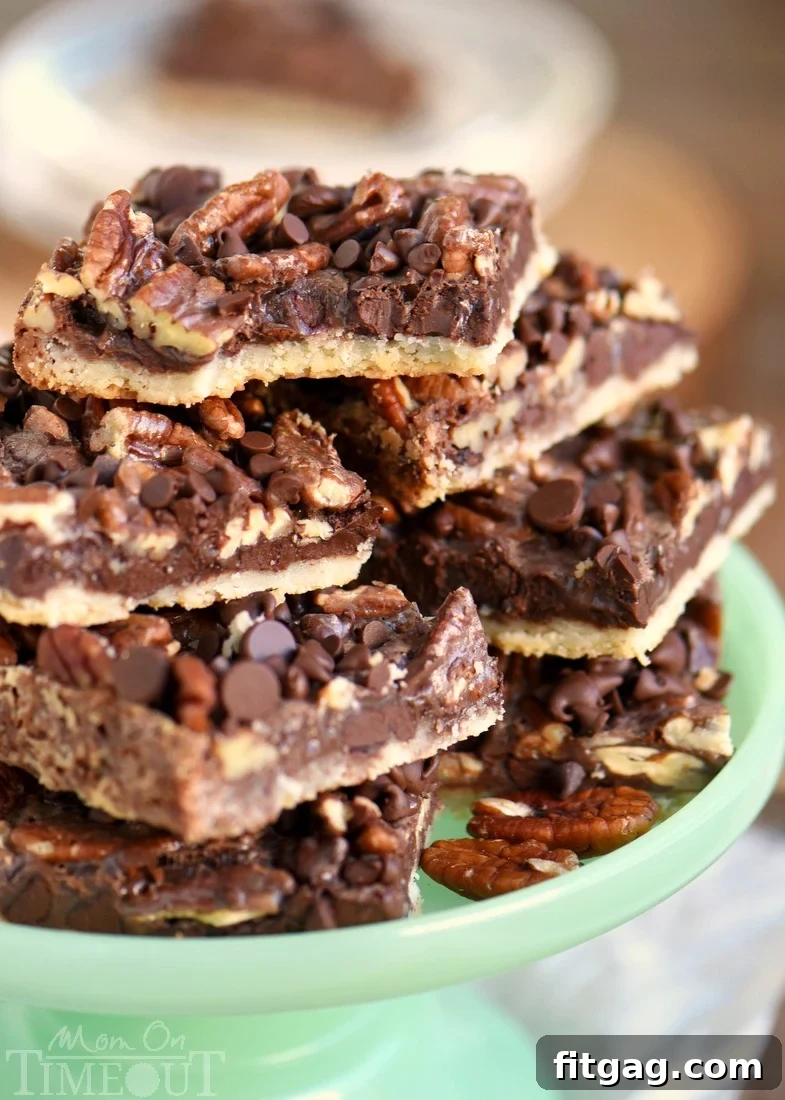 Pecan pie bars piled high on a green cake stand, showcasing their rich chocolate and pecan layers. A perfect easy holiday dessert for a crowd.