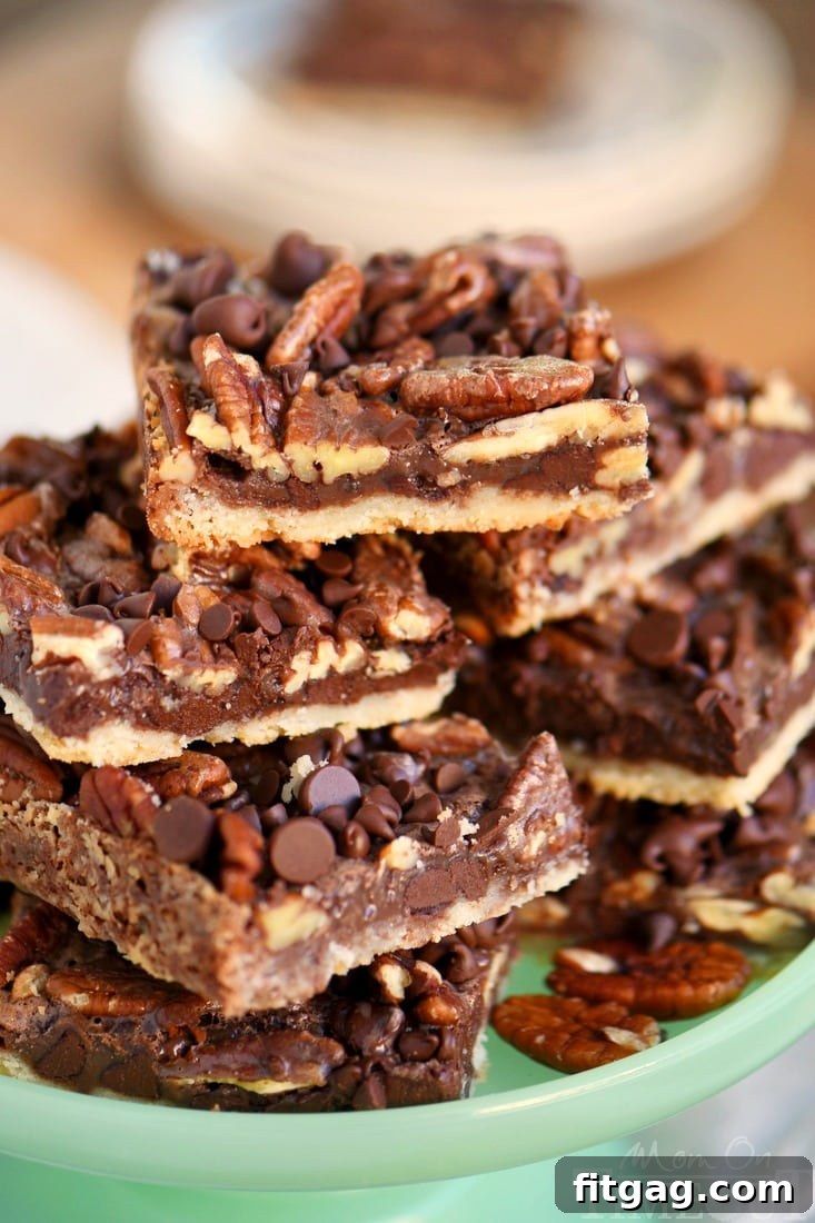 Stacked chocolate pecan pie bars displaying their delicious layers of crust, chocolate, pecans, and gooey filling. Ideal for holiday dessert tables.