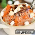 mashed sweet potatoes topped with marshmallows and pecans in beige bowl