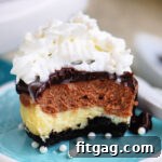 Mini cheesecake split in half to show chocolate and vanilla marbled layers, topped with ganache and whipped cream on a small green plate.