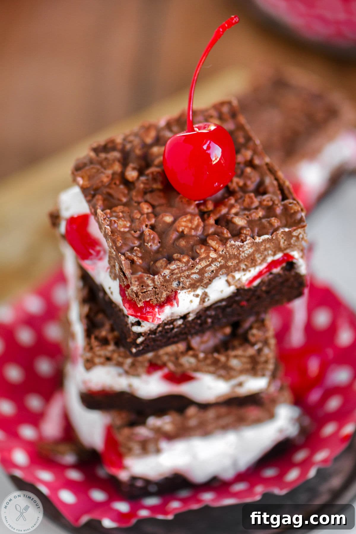 Cherry Brownie Bliss Bars 3 Angle overhead shot of cherry brownie marshmallow bars with crispy peanut butter chocolate topping, arranged on red and white polka dot cupcake liners.
