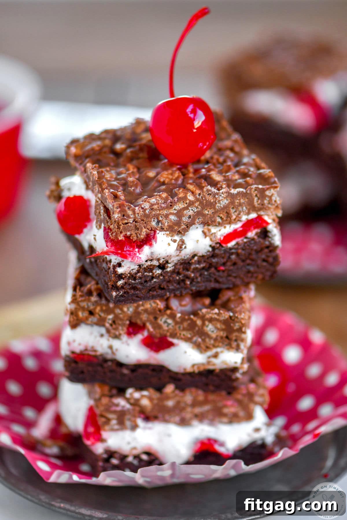 Cherry Brownie Bliss Bars 6 Stack of three cherry brownie dream bars on a metal plate with a maraschino cherry on top, highlighting the delicious layers and garnish.