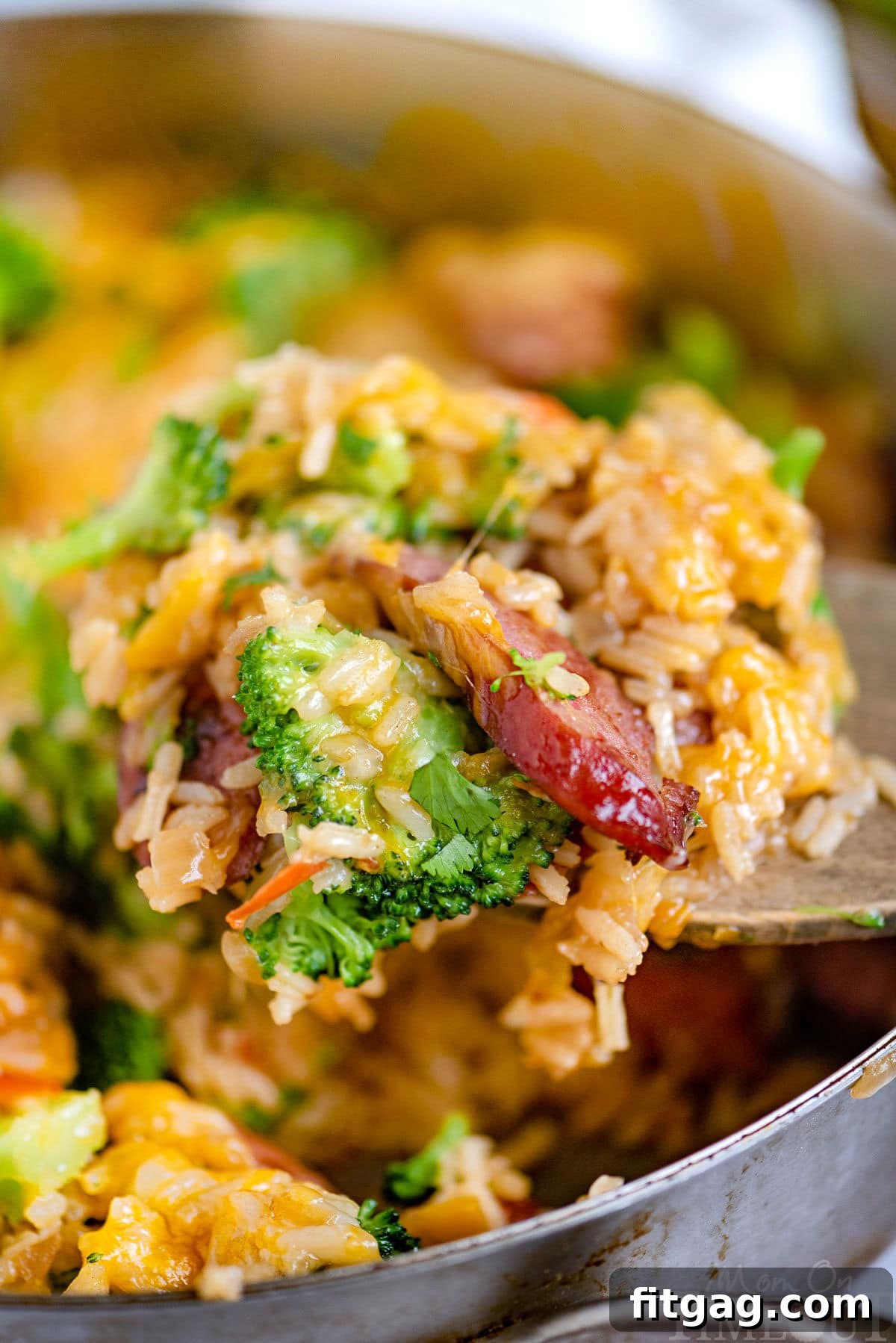 One-Skillet Cheesy Kielbasa and Broccoli Rice 2 Scoop of cheesy kielbasa broccoli skillet recipe being held over the skillet.