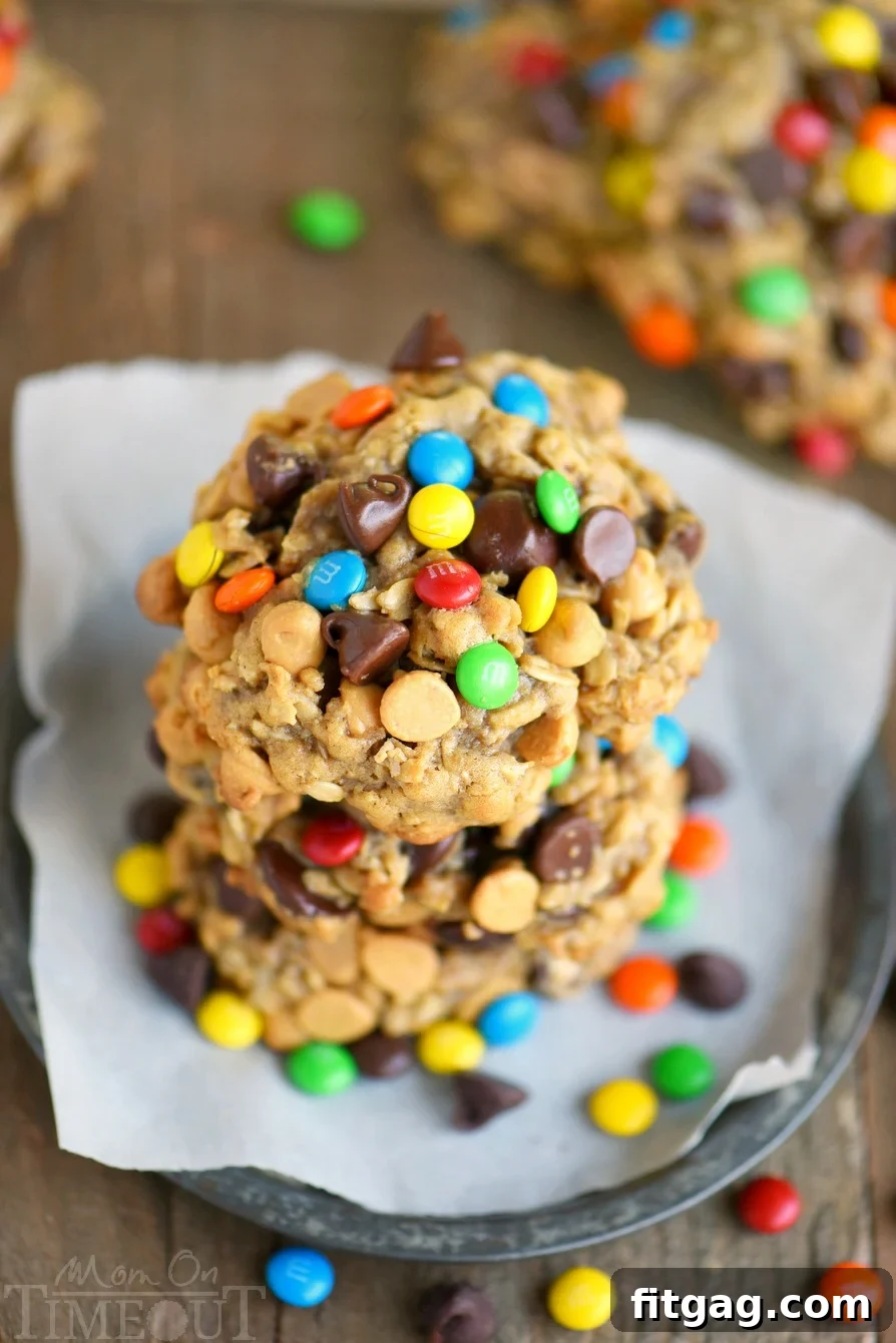 Epic Peanut Butter Oatmeal Cookies 3 Close-up of Monster Peanut Butter Oatmeal Cookies stacked on a white plate, showcasing the chocolate chips, M&M's, and oatmeal texture.