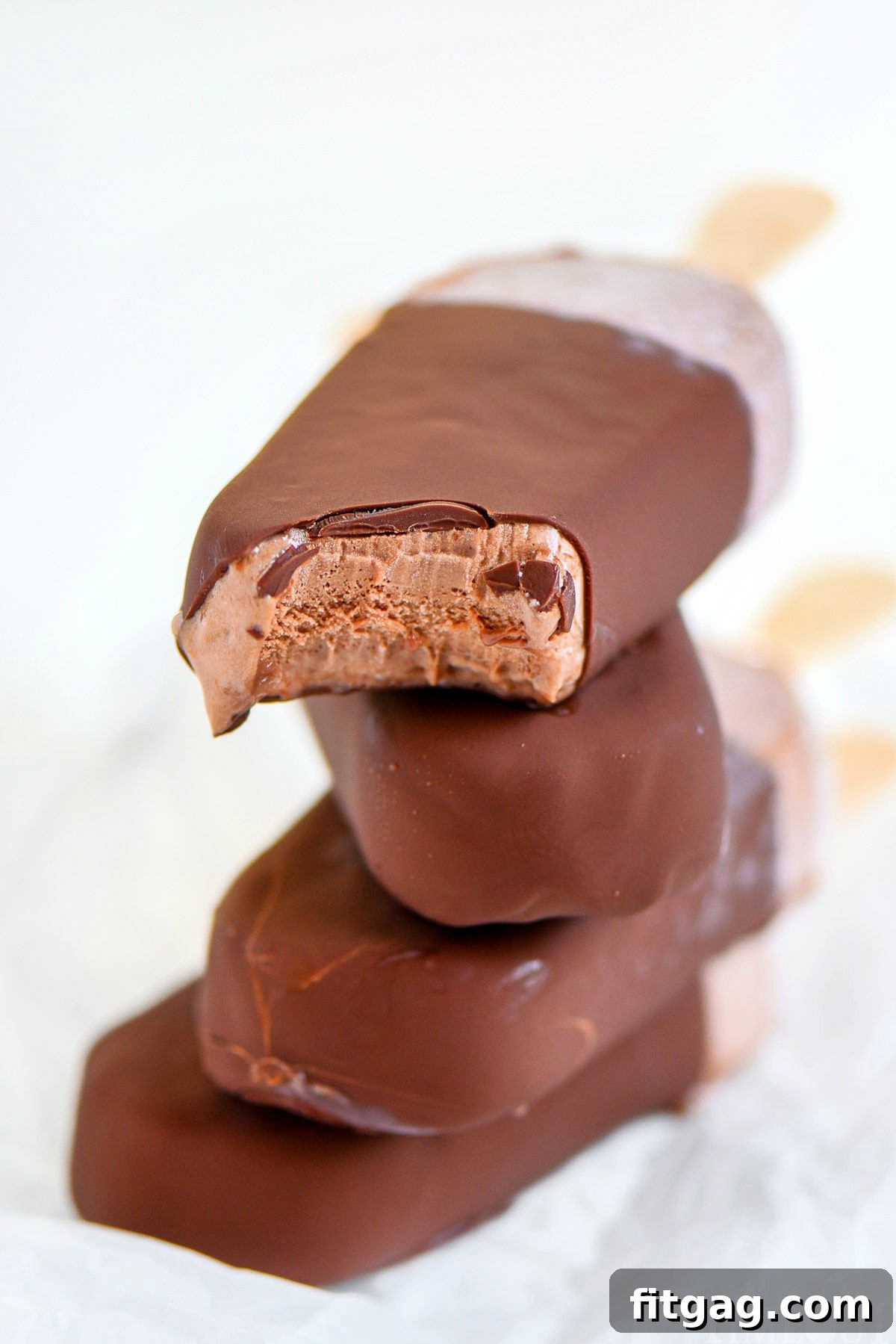 Four fudge bars that have been dipped in chocolate magic shell, stacked appealingly with popsicle sticks visible.