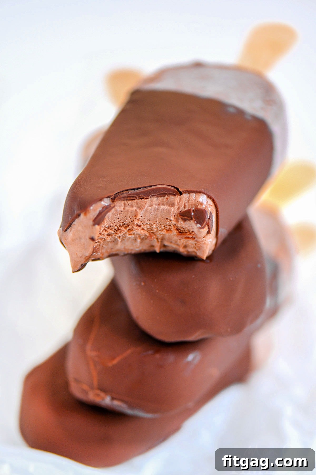 Four fudge bars that have been dipped in chocolate magic shell, stacked appealingly with popsicle sticks visible.