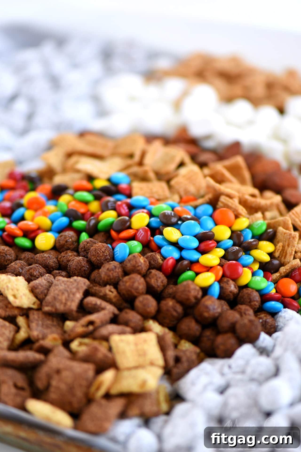 Finished Monster S'mores Muddy Buddies spread out on parchment paper, displaying the colorful additions.