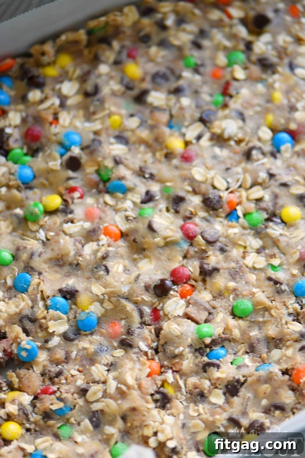 A closer look at the layers of homemade Monster Fudge Bars, showcasing the thick, chocolatey fudge generously topped with colorful M&M's, ready to be sliced and enjoyed.