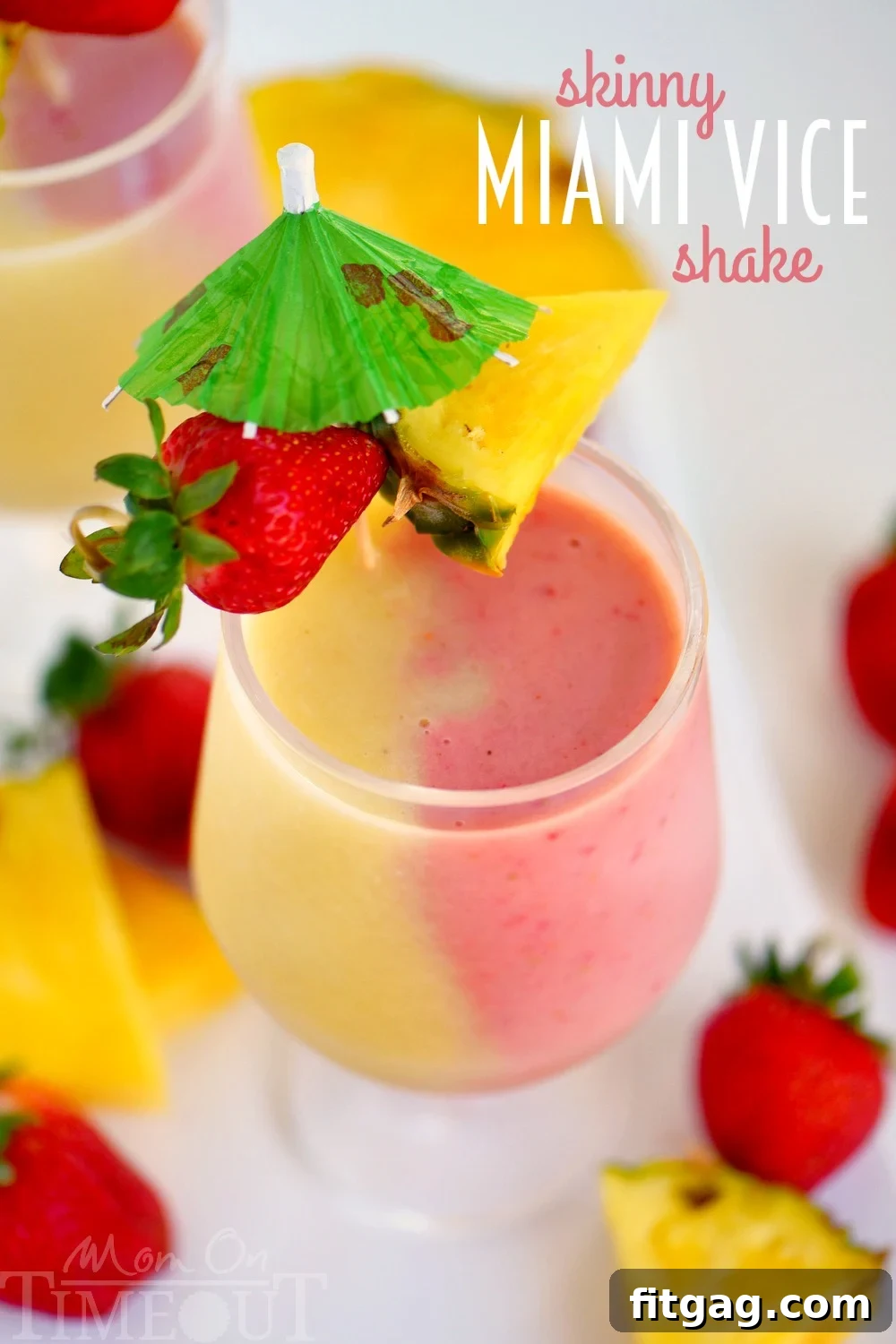 A tall glass showcasing the beautifully layered Skinny Miami Vice Shake, with creamy white pina colada on the bottom and a vibrant red strawberry daiquiri on top, garnished with fresh strawberry and pineapple, ready to refresh on a hot day.