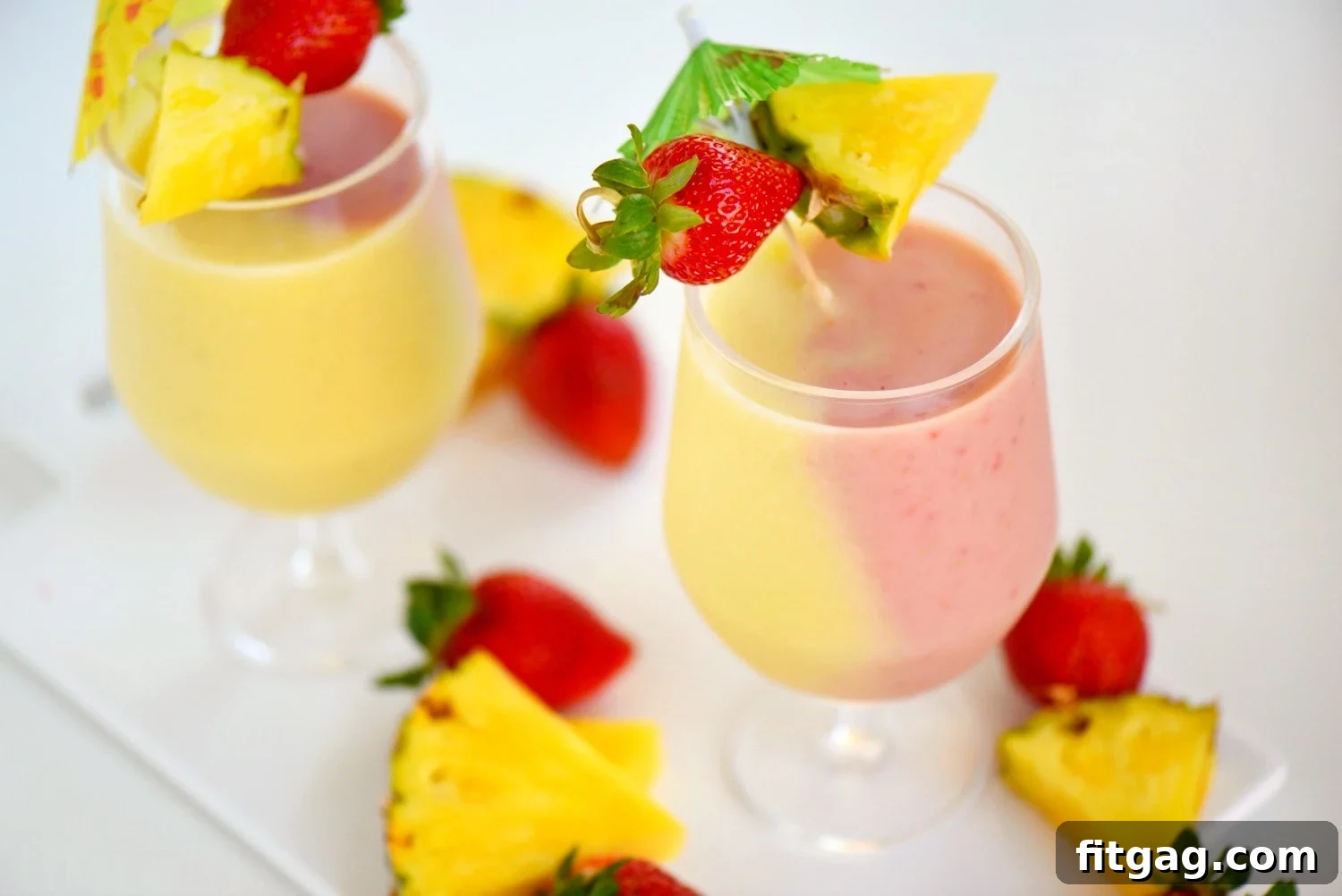 A festive Skinny Miami Vice Shake, garnished with fresh pineapple and strawberries, resting on a wooden tray with a tropical leaf accent, symbolizing a perfect vacation drink.