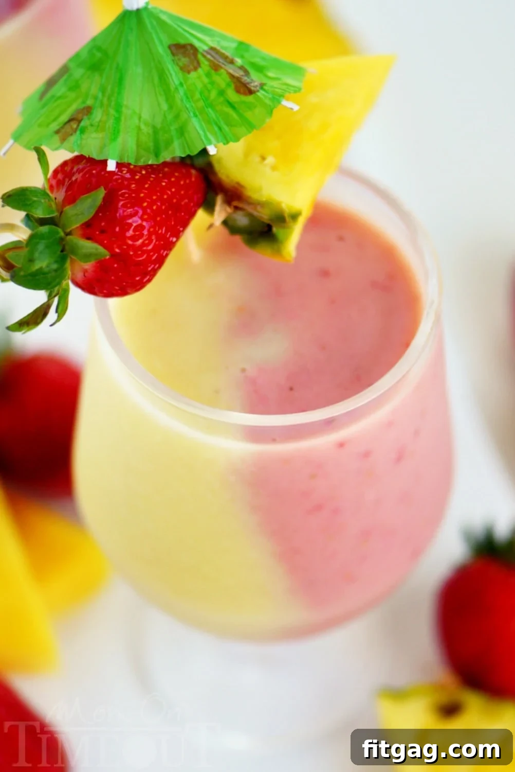 A vibrant Skinny Miami Vice Shake, garnished with a strawberry, pineapple wedge, and a tiny cocktail umbrella, perfectly presented for a refreshing summer treat.