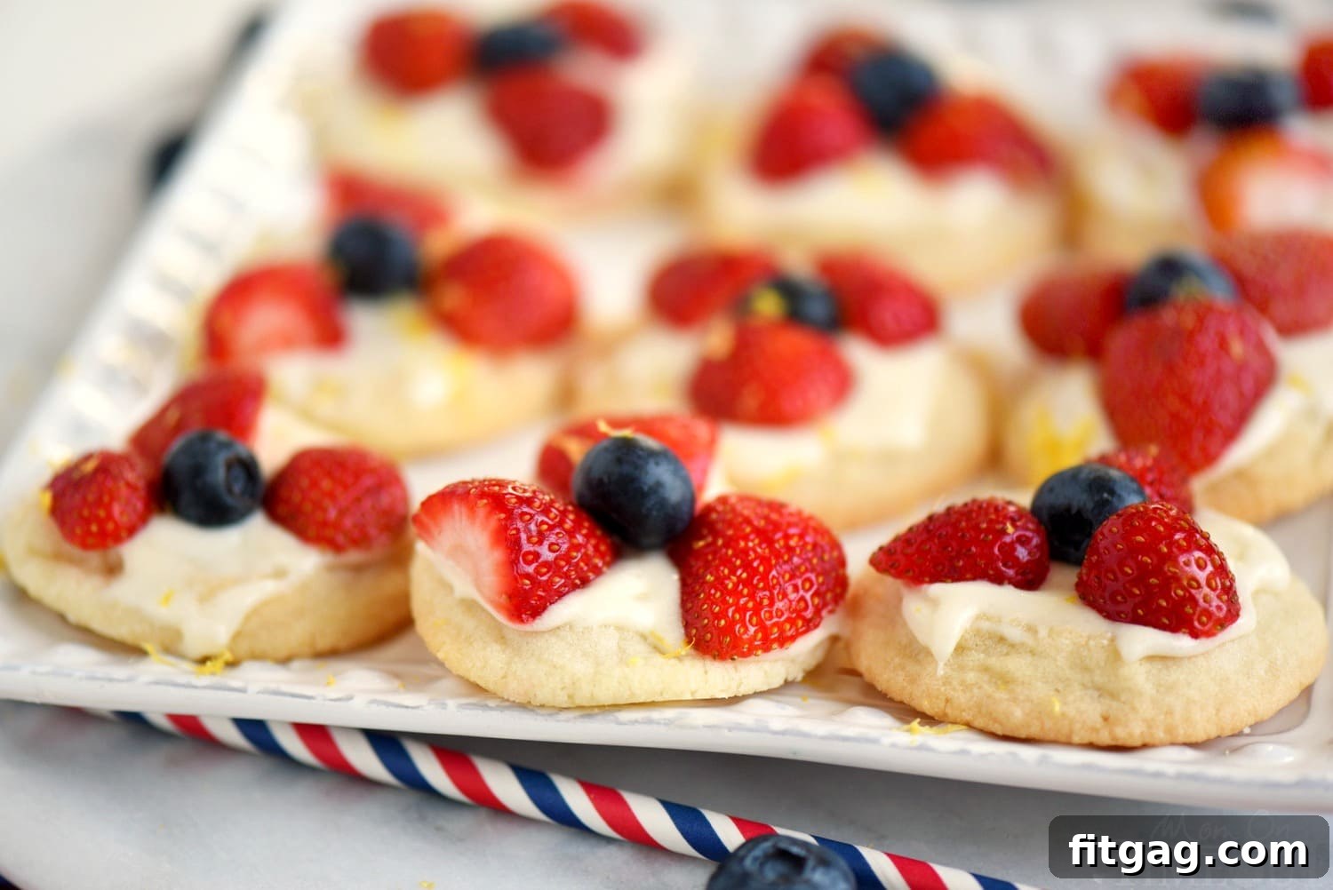 Hand reaching for a Berries 'N Cream Cookie from a serving platter, showcasing the dessert's irresistible appeal.