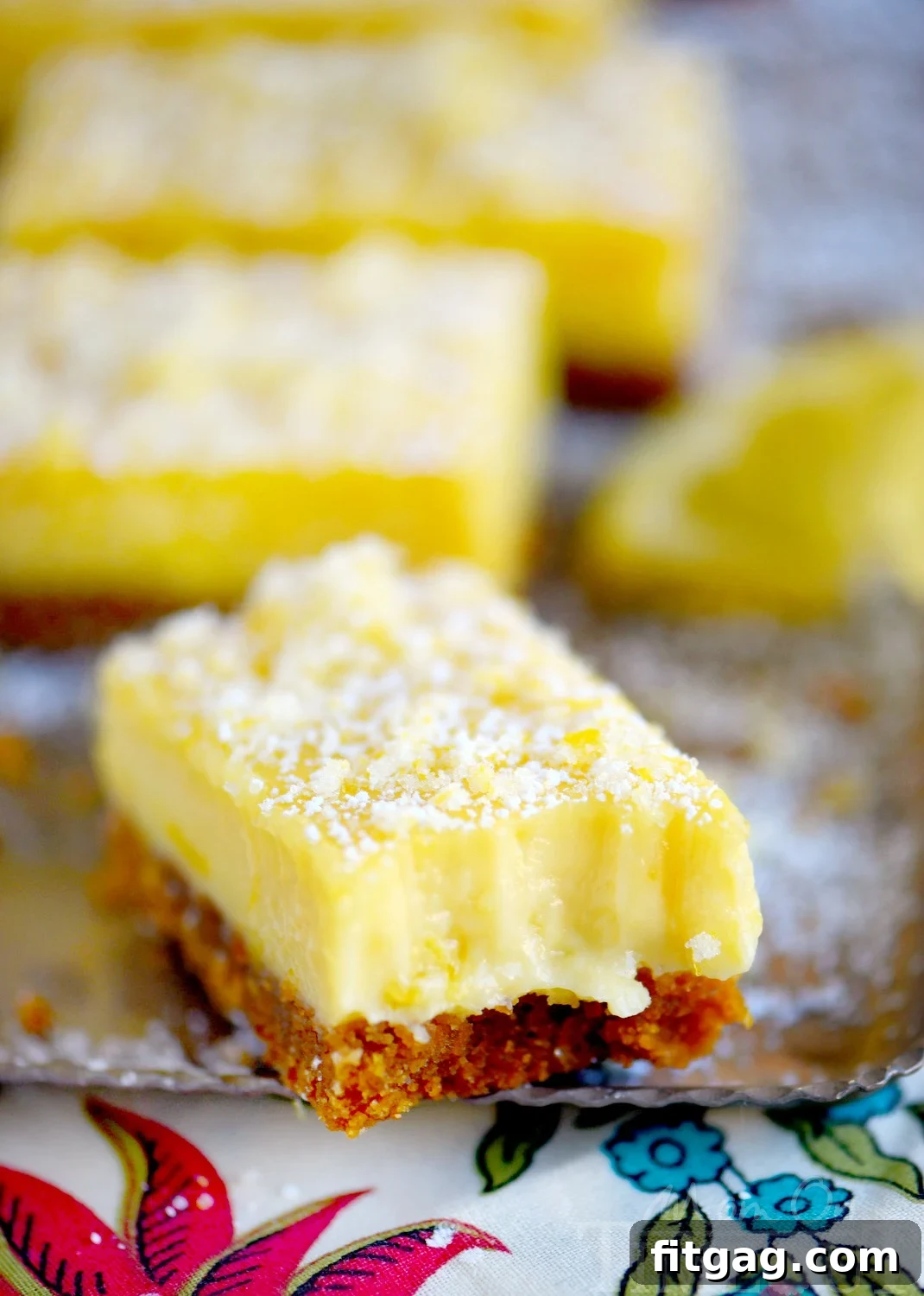 Individual Lemon Drop Bars with a dusting of powdered sugar and candied lemon zest, ready to be enjoyed.