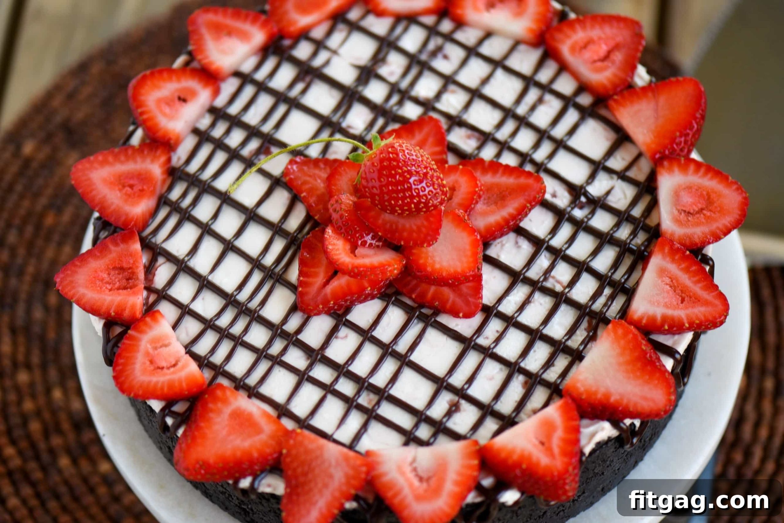 Strawberry Cloud Cheesecake 3 Close-up of a slice of No-Bake Strawberry Cheesecake revealing the OREO crust, thick chocolate ganache, and creamy strawberry filling, topped with fresh berries.