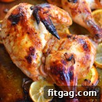 top down look at half a chicken roasted with a lemon and orange glaze sitting on a sheet pan.