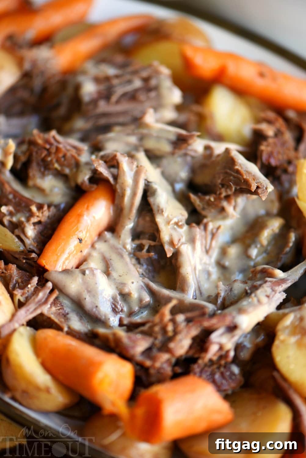 A perfectly cooked pot roast, plated with rich gravy and colorful root vegetables, ready to be served.