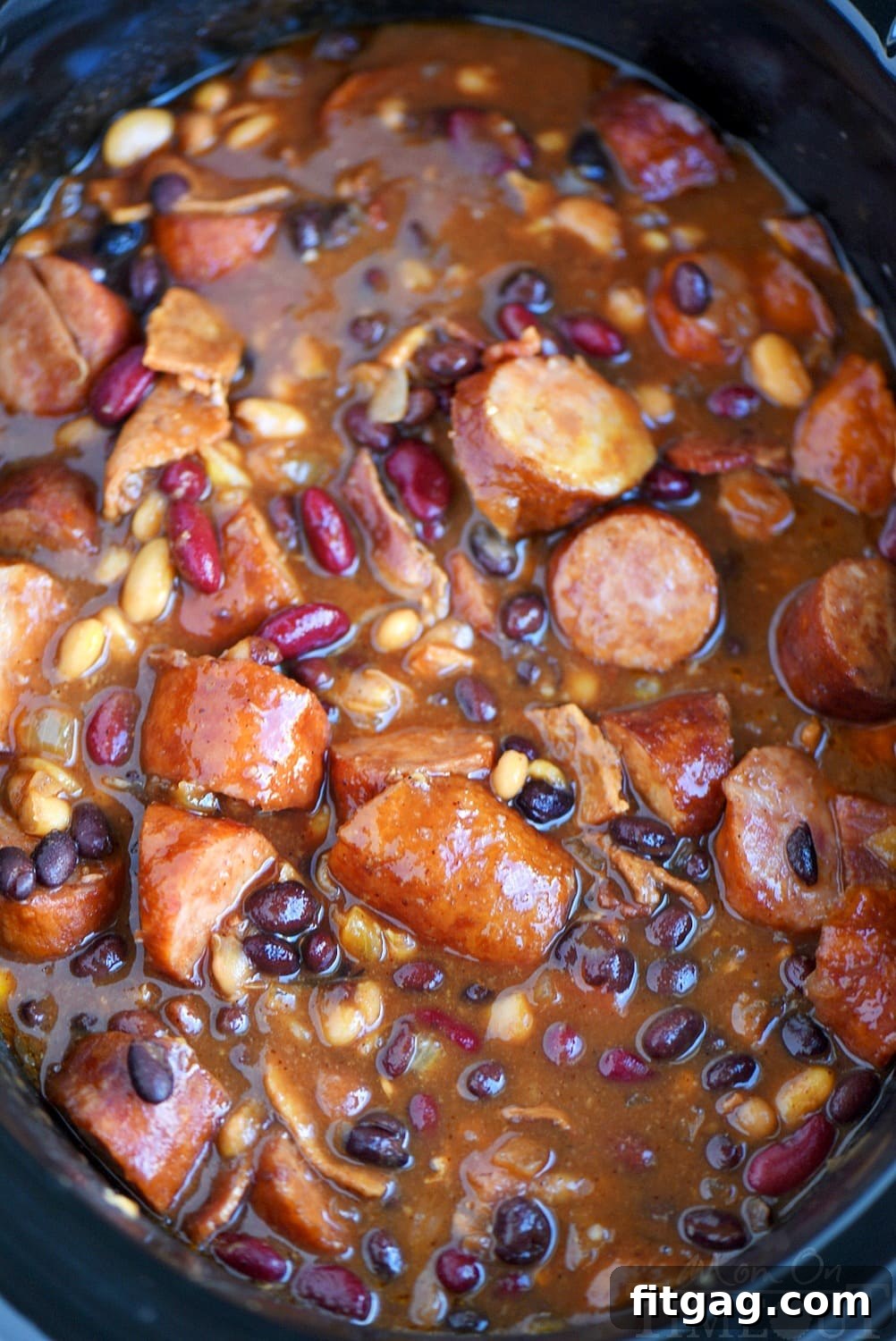Slow Cooker Kielbasa and Barbecue Beans is the perfect chilly day recipe! Made with three different beans, molasses, bacon, and kielbasa - it's pure comfort food! // Mom On Timeout #slowcooker #crockpot #recipes #bacon #beans #bbq #kielbasa #comfortfood #dinnerideas #recipe Finished Slow Cooker Kielbasa and Barbecue Beans in the crockpot, ready to be served.