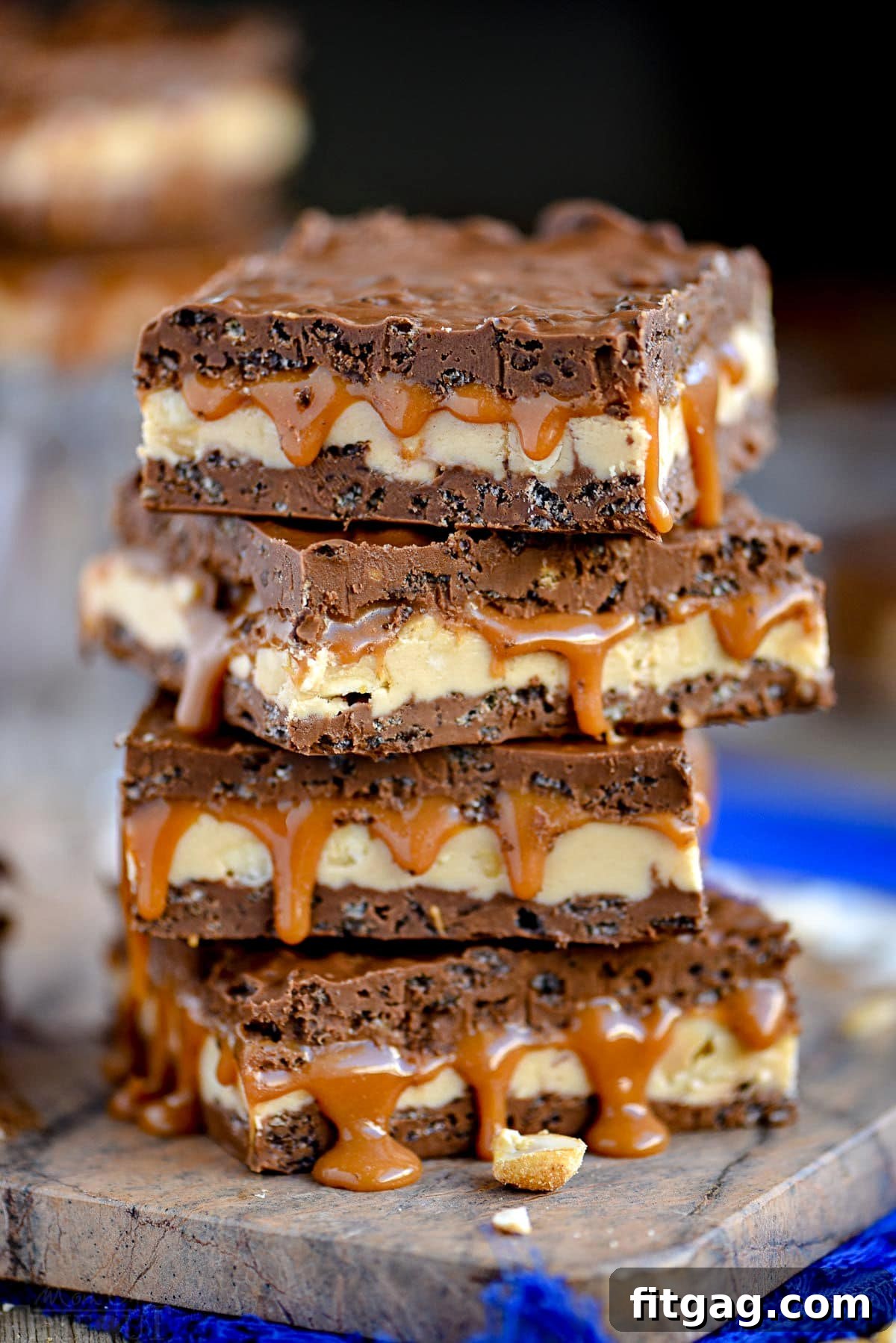 four snickers bars stacked on marble cutting board sitting on a blue napkin.