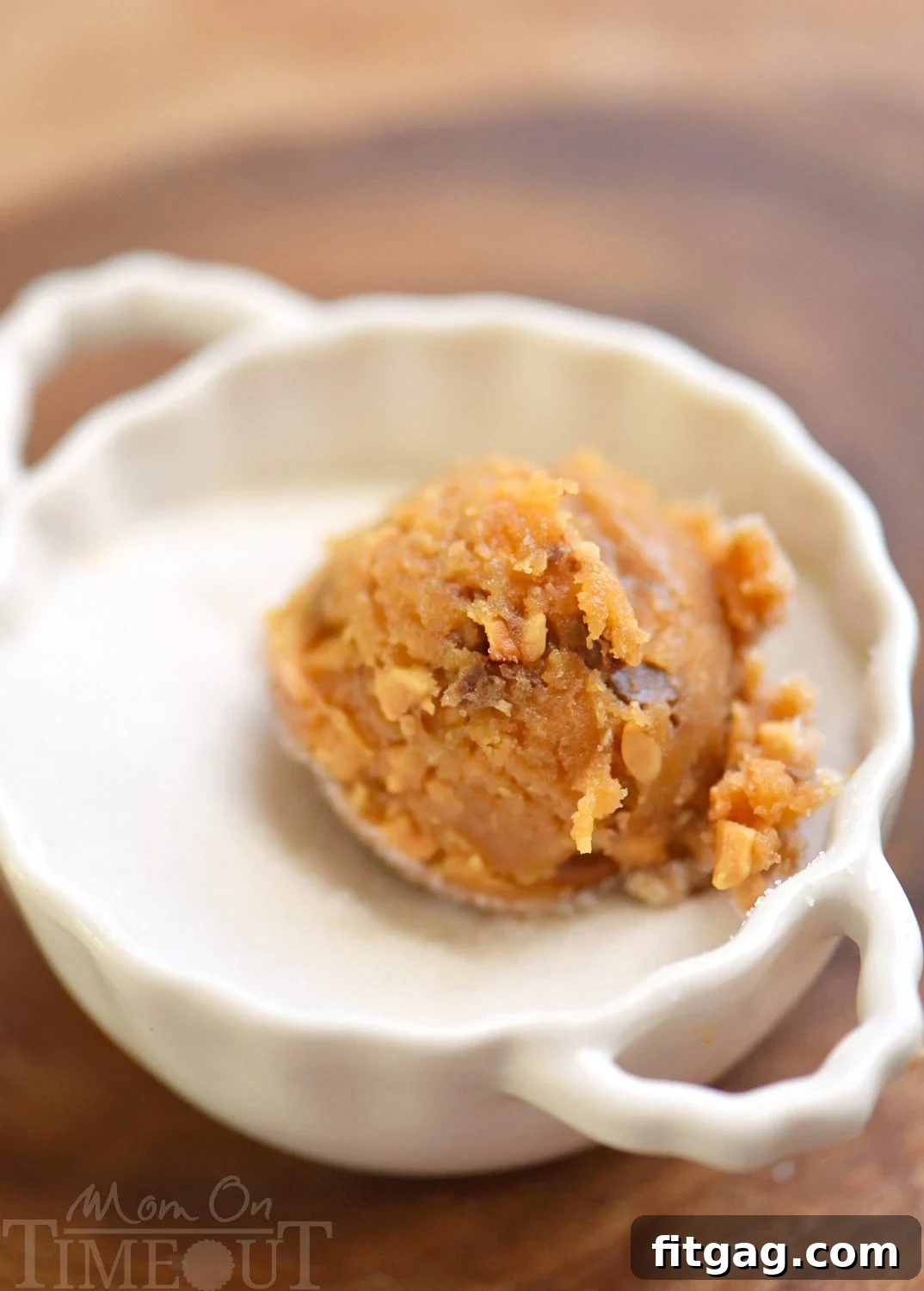 Peanut butter cookie dough balls rolled in granulated sugar on a parchment-lined baking sheet, ready for the signature criss-cross.