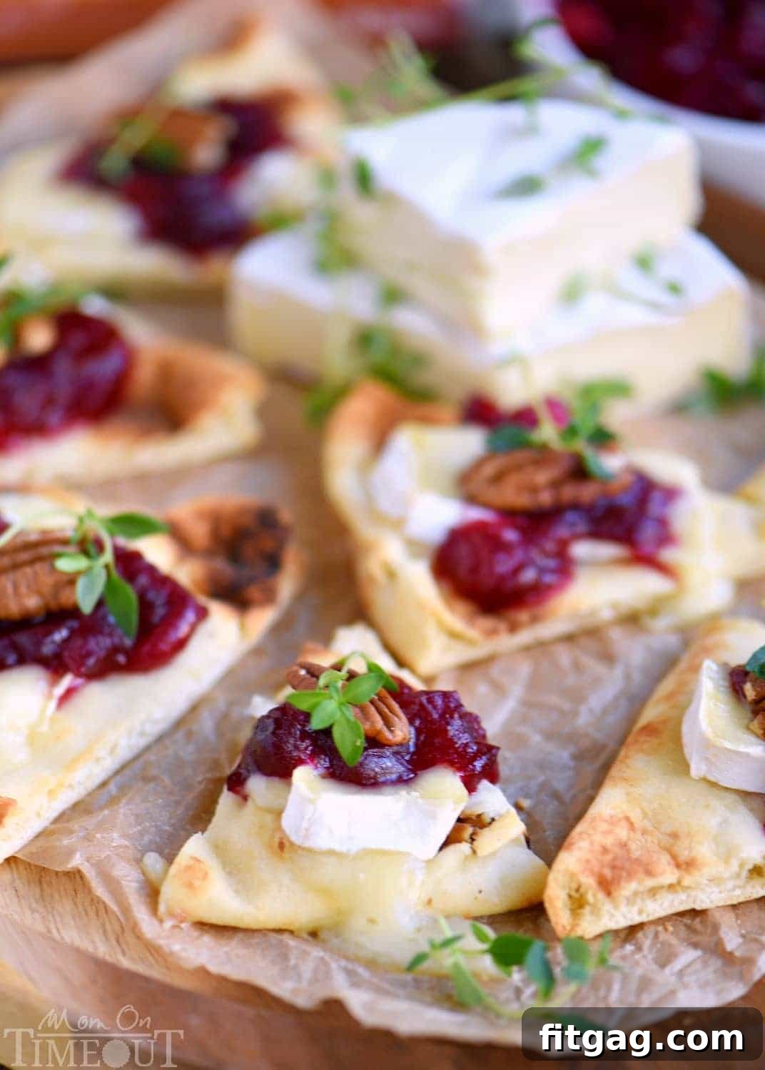 Closeup of Cranberry Pecan Brie Bites showing melted cheese and fresh thyme garnish on naan bread