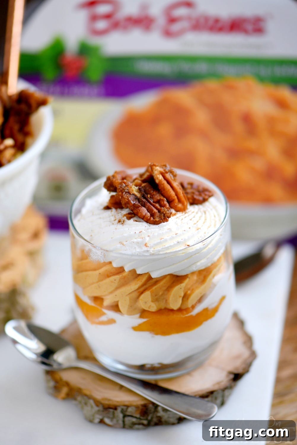 A single sweet potato cheesecake parfait in a glass jar, with a small spoon resting against it, highlighting the vibrant layers and the golden hue of the sweet potato.