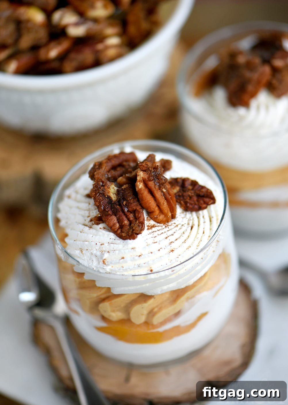 An overhead shot of four sweet potato cheesecake parfaits in glass jars, garnished with candied pecans and a light dusting of cinnamon, ready for serving.