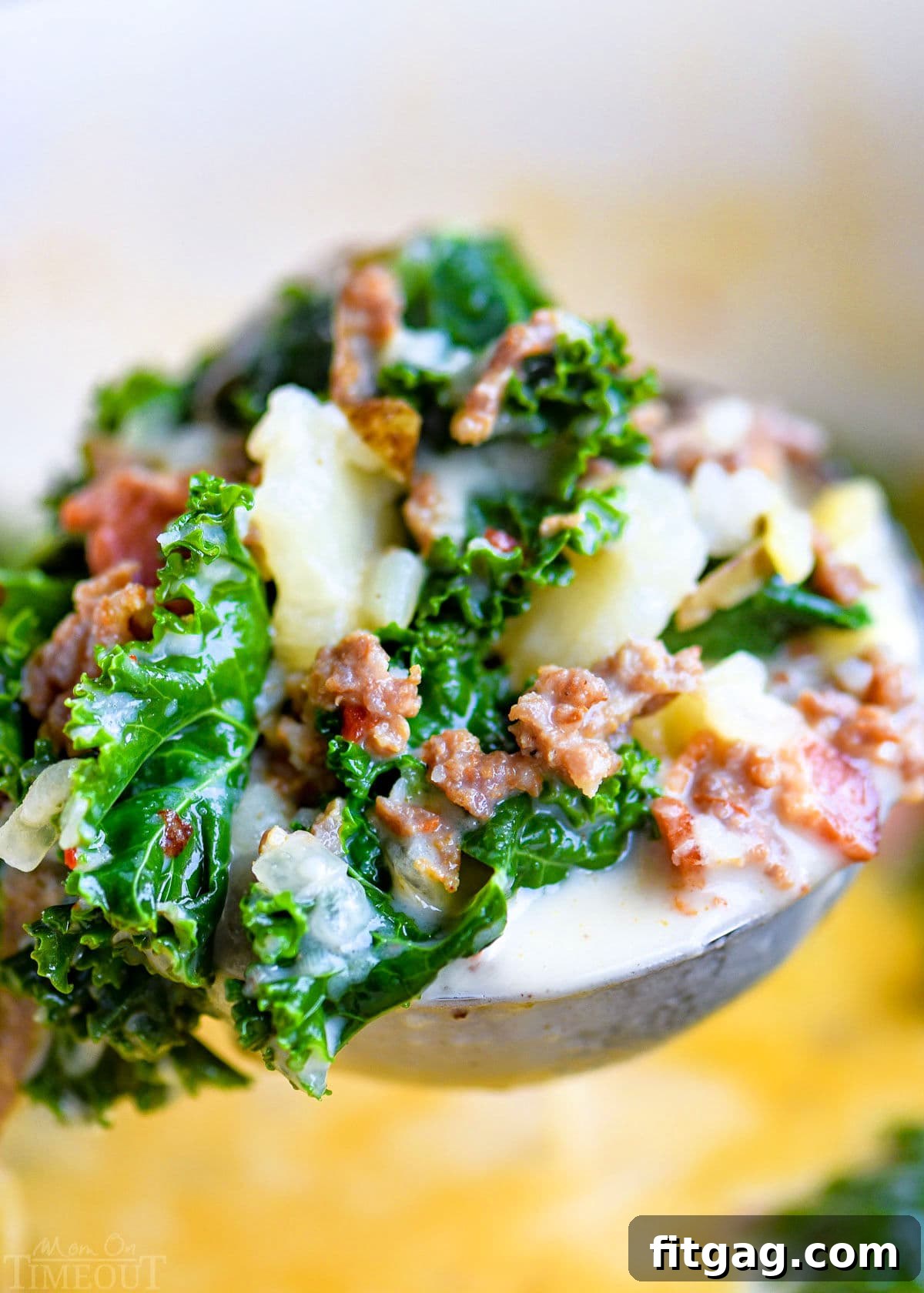 Hearty Tuscan Farmhouse Soup 3 A ladle full of creamy Zuppa Toscana soup, showing visible pieces of kale, potatoes, and savory sausage, held above the simmering pot of soup.