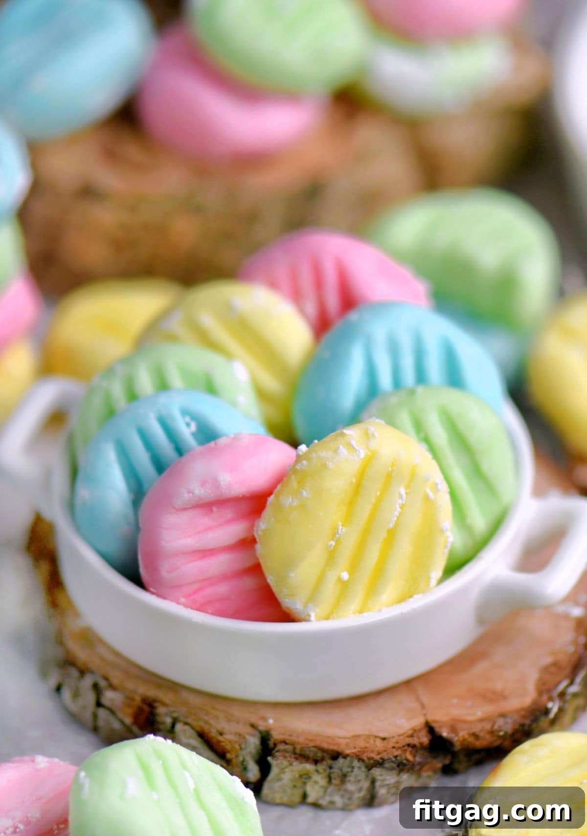Ultimate Cream Cheese Mints 2 Colorful pastel cream cheese mints in white shallow dish sitting on wood surface.