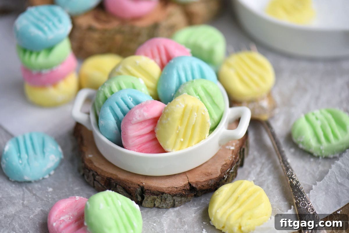 Ultimate Cream Cheese Mints 6 Colorful pastel cream cheese mints in white shallow dish sitting on wood surface. More mints are scattered around the bowl.