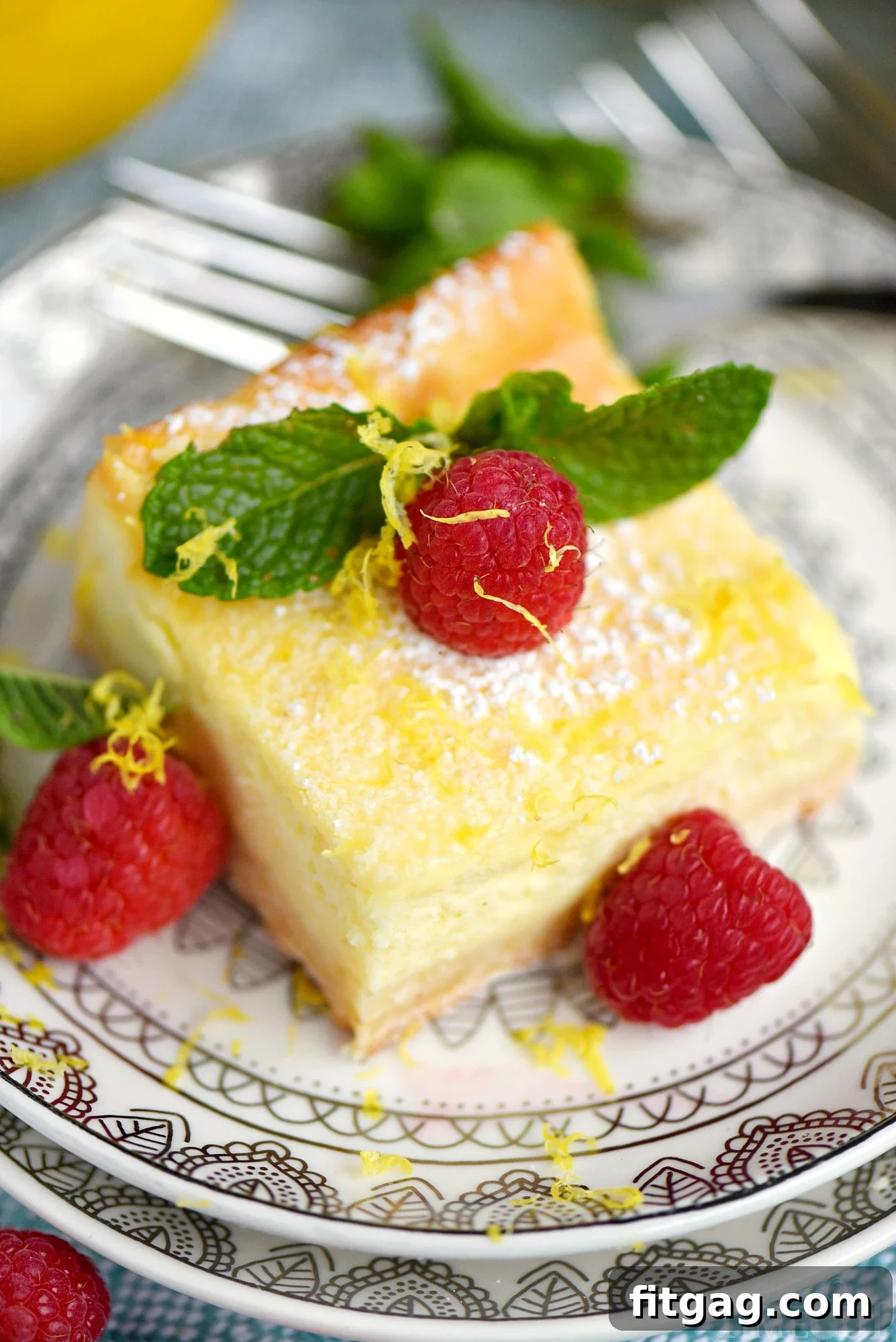 Zesty Lemon Cheesecake Bars 4 My Aunt Pam's Lemon Cheesecake Bars are made with lots of fresh lemon juice and zest so they're bursting with lemon flavor! Extra creamy, super easy and always a crowd pleaser! Top with powdered sugar, fresh raspberries, and extra lemon zest for a pretty presentation! // Mom On Timeout