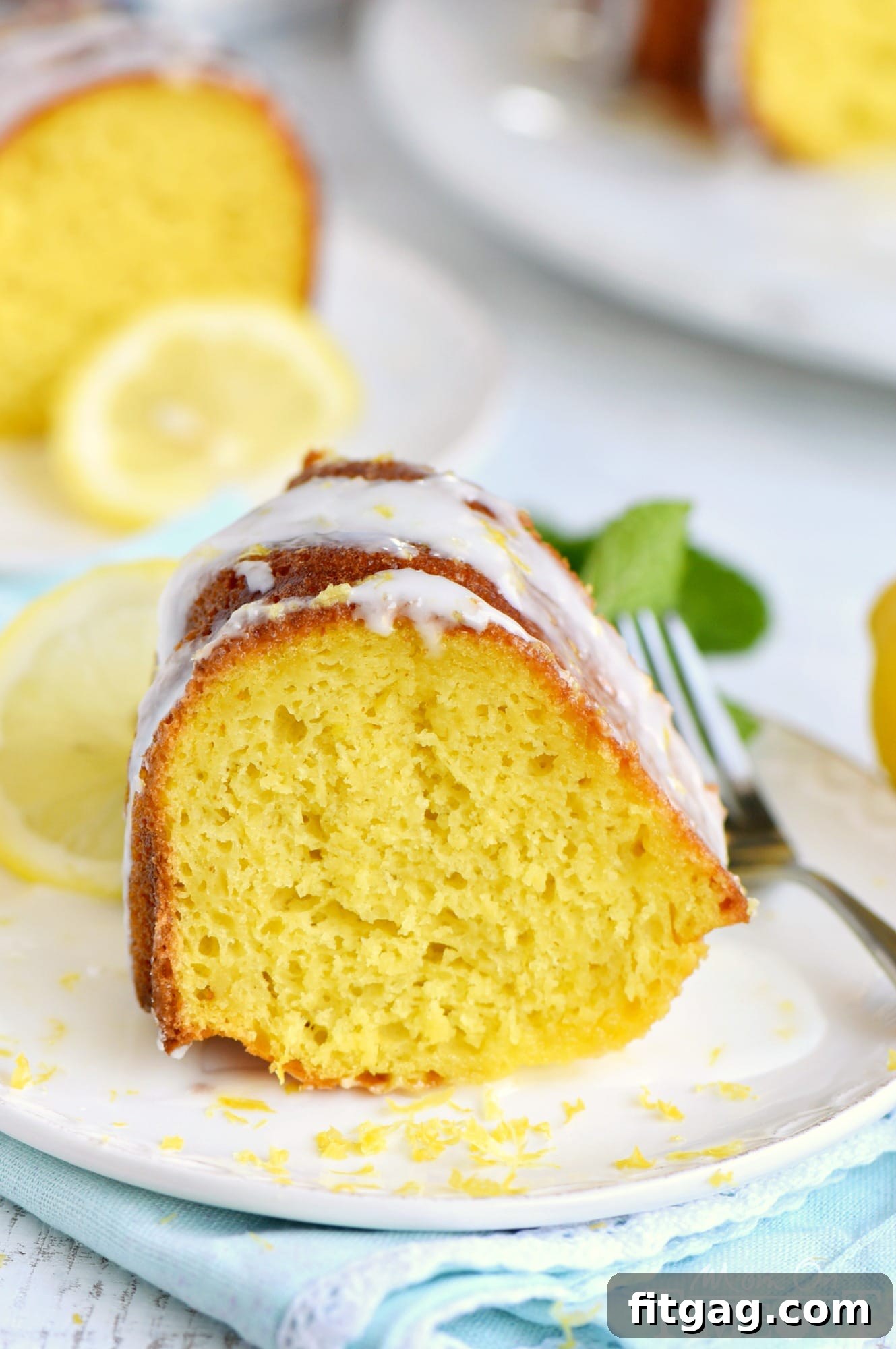 Golden Lemon Bundt Bliss 3 Close-up of a slice of Easy Lemon Bundt Cake, revealing its moist texture and vibrant yellow color, topped with a luscious glaze.