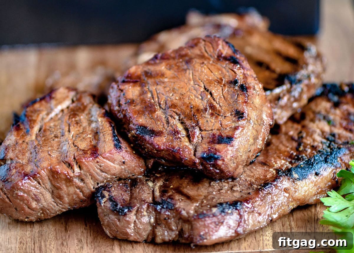The Ultimate Steak Marinade 6 Cooked steaks, beautifully seared with distinct grill marks, resting on a wooden cutting board, ready to be sliced and served.
