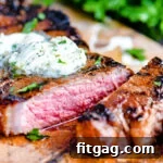 The Ultimate Steak Marinade 7 Steak on cutting board with compound butter melting on top. One piece cut off of steak with fresh parsley in the background.