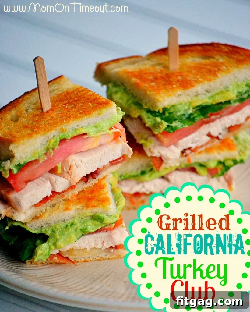 Grilled California Turkey Club sandwich with avocado and bacon on a small lunch plate, garnished with a sprig of rosemary