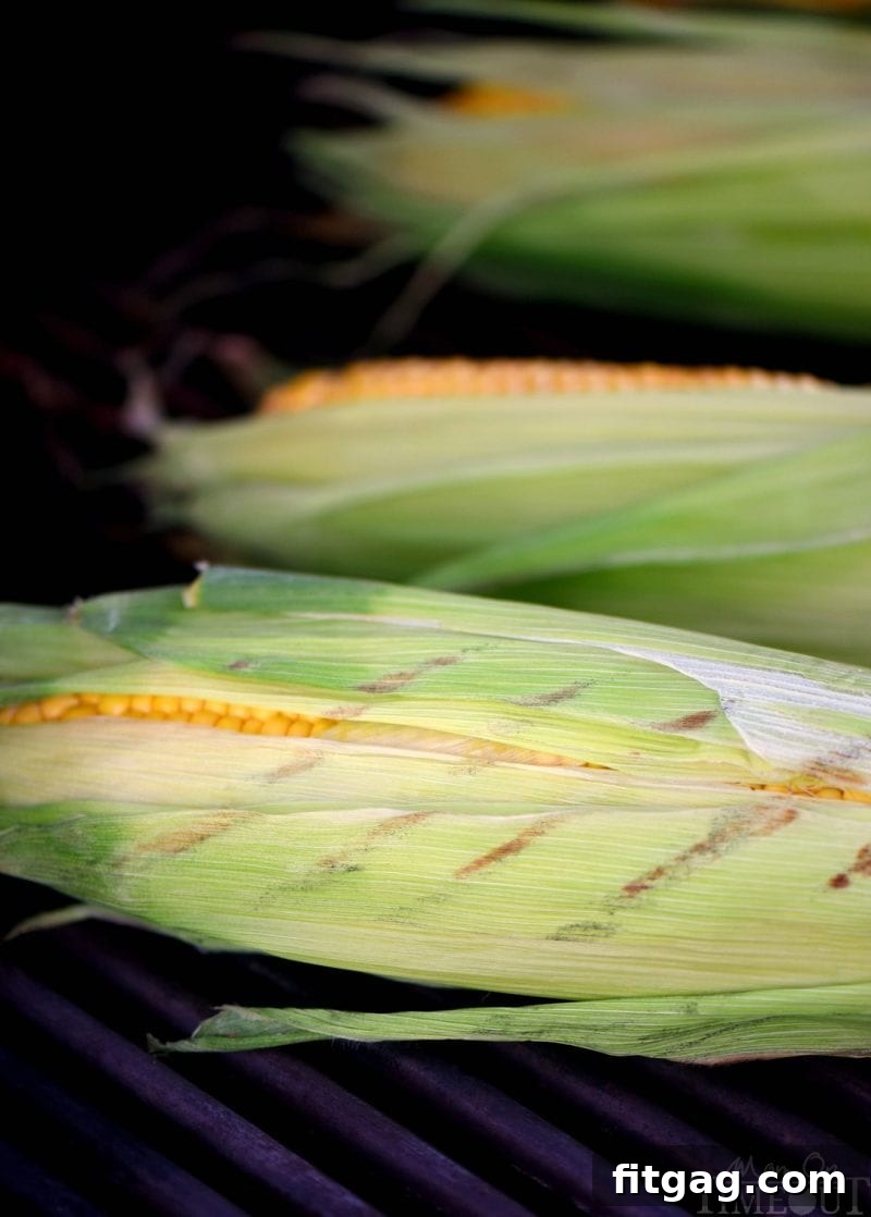 Flame-Kissed Corn with Aromatic Herb Butter 5 Detailed shot showing the process of pulling back corn husks and removing silks, revealing fresh kernels ready for grilling.