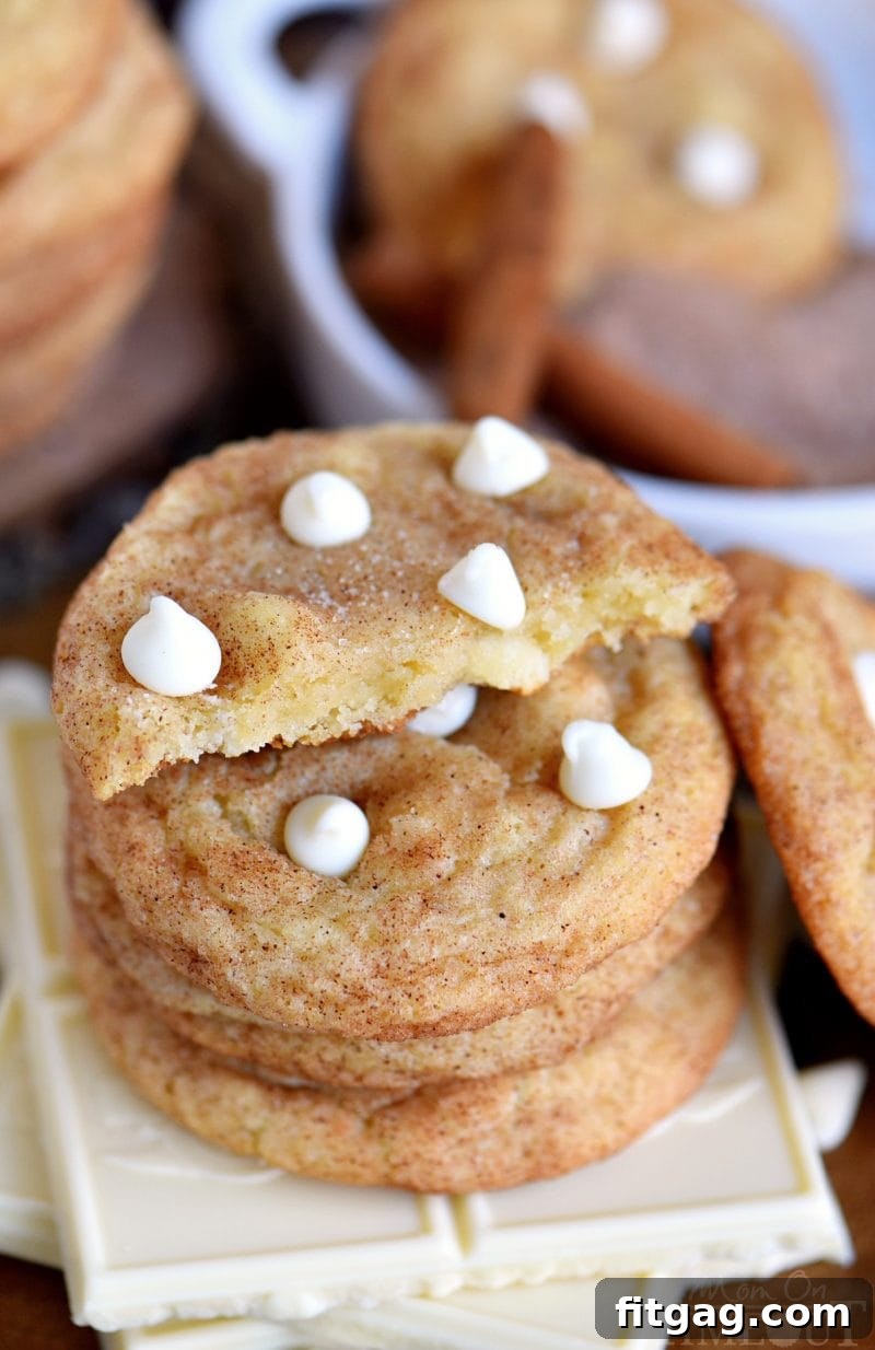 Easy White Chocolate Snickerdoodles in a stack, with the top cookie expertly cut in half to reveal its soft, chewy interior.