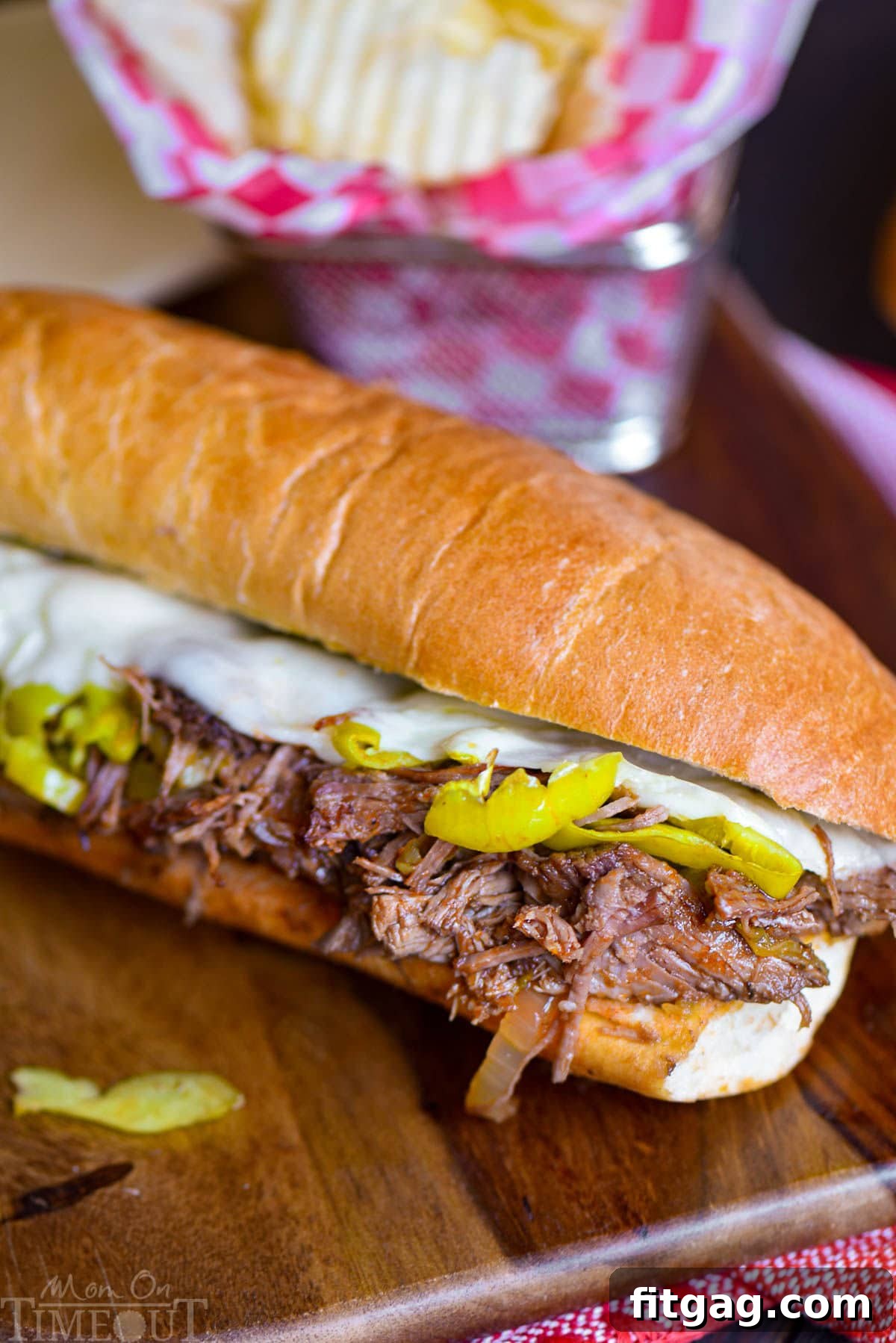 Melt-in-Your-Mouth Slow Cooker Italian Beef Sandwiches 6 Italian Beef Sandwich recipesitting on wood cutting board with a basket of chips behind it.