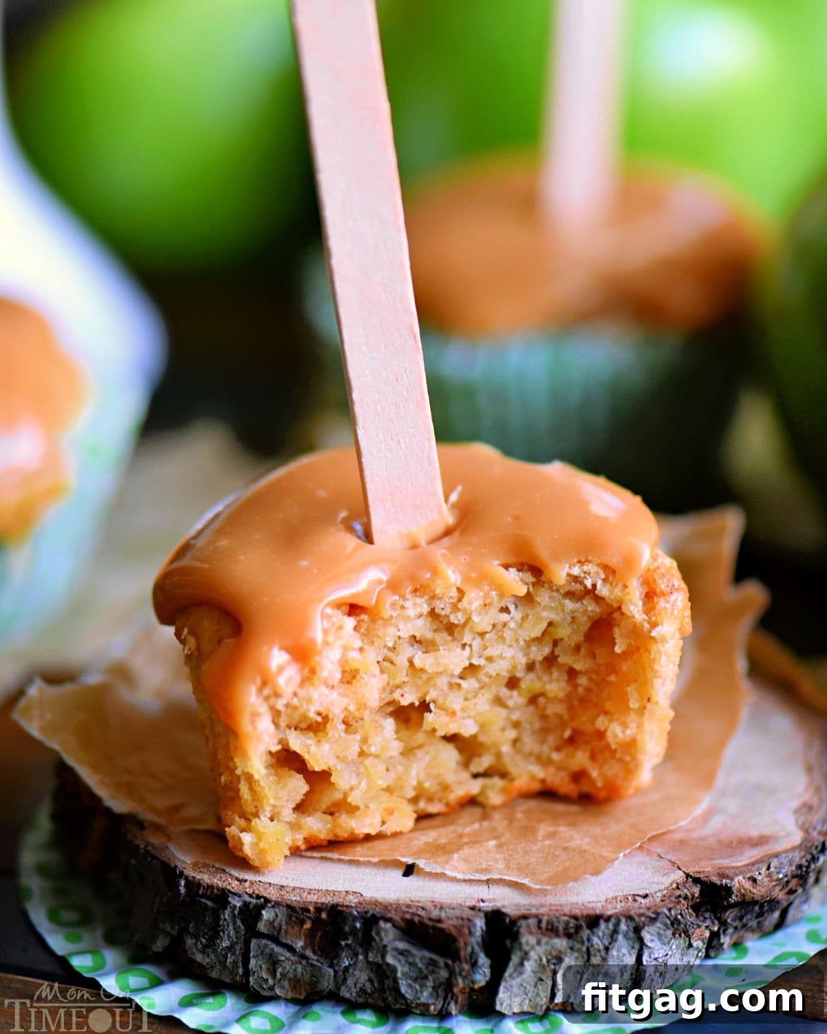 Autumn Caramel Apple Delights 3 Close-up shot of a caramel apple cupcake with a bite taken out, resting on a small wooden coaster, showcasing the moist interior and thick caramel topping.