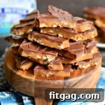broken up toffee topped with chocolate sitting on a small round wood serving board.