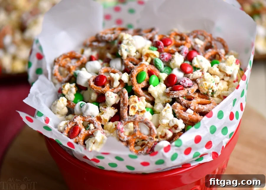 A close-up of a festive Snow Day Snack Mix, showcasing the sweet and salty combination of ingredients like popcorn, pretzels, candies, and marshmallows, coated in white chocolate.