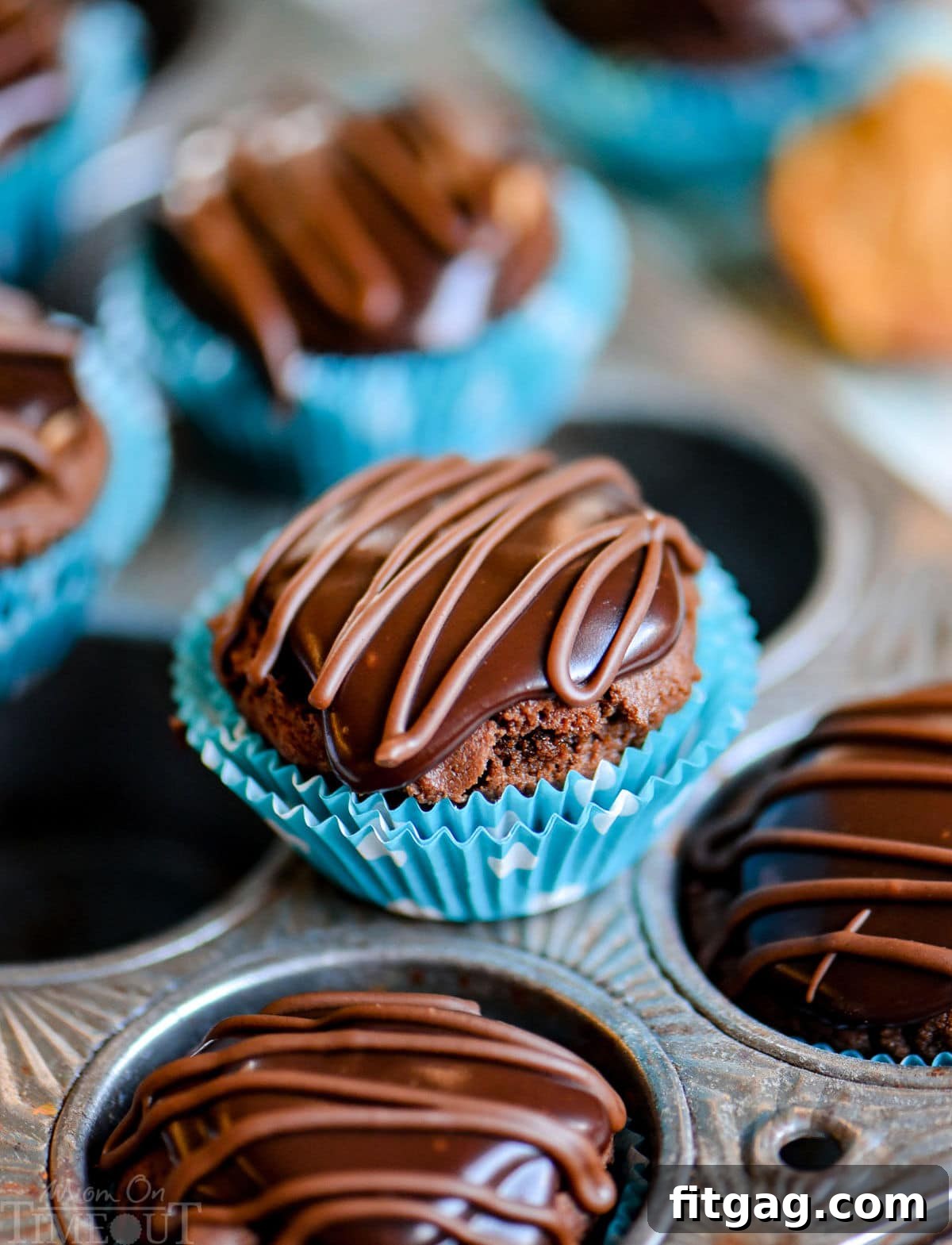 A perfectly formed Buckeye Bite in a polka dot mini muffin liner, sitting alongside other delightful treats on a muffin pan, ready to be enjoyed.