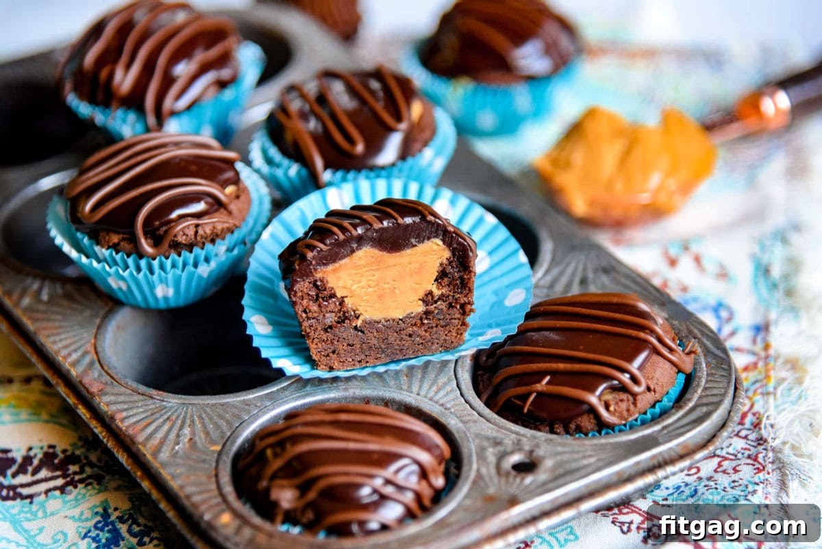 A charming close-up of a half-eaten Buckeye Bite, revealing its creamy layers, nestled among other cookies on a rustic mini muffin pan.