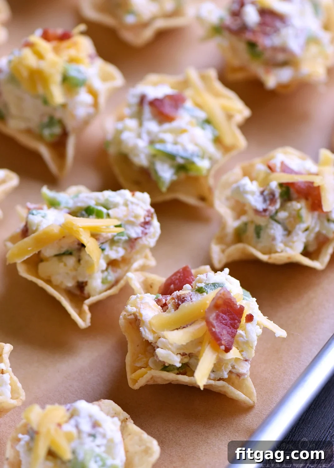 Hands preparing Easy Jalapeño Popper Bites, showing the filling being scooped into tortilla chips. Highlights the simplicity of preparation.
